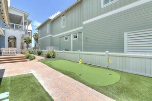 A residential area with a paved walkway, a small lawn, and a white fence. - Palmilla Beach Resort-137 Sunrise Avenue (Port Aransas)