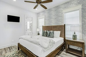 A bedroom with a bed, a nightstand, a ceiling fan, and a wall-mounted TV. - Palmilla Beach Resort-138 Sunset Avenue (Port Aransas)