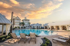 Ein Poolbereich eines Resorts mit Liegestühlen, einem großen Pool und den Gebäuden des Resorts.