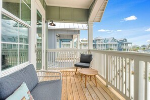 A wooden deck with a sofa and a chair, a railing, and a view of houses in the background. - Palmilla Beach Resort-144 Sabal Lane (Port Aransas)