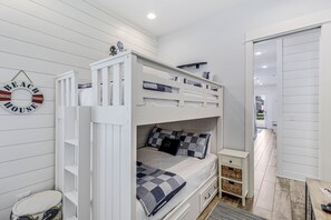 Ein Etagenbett mit Kopfteil und Fußteil, ein kleiner Nachttisch, ein an der Wand befestigtes Regal und ein Wandbild.