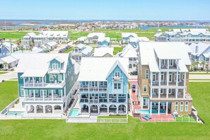A large, multi-story house with a swimming pool, multiple balconies, and a view of the ocean. - Palmilla Beach Resort-144 Sunrise Avenue (Port Aransas)