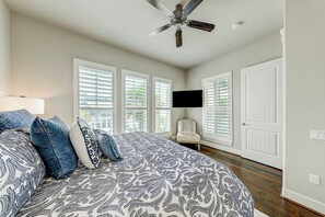 A bedroom with a bed, a ceiling fan, a TV mounted on the wall, and a window with blinds. - Palmilla Beach Resort-145 Sunrise Avenue (Port Aransas)