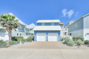 A residential building with a two-story structure, a front garage, and a palm tree. - Palmilla Beach Resort-145 Sunrise Avenue (Port Aransas)