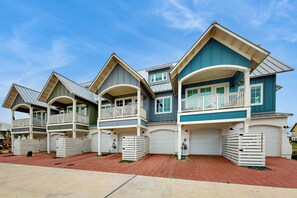 A row of two-story houses with attached garages, featuring balconies and a brick driveway. - Palmilla Beach Resort-146 Sabal Lane (Port Aransas)