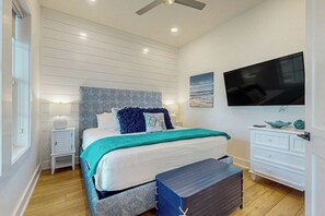 Ein Schlafzimmer mit einem Bett, Nachttischen, einem Schminktisch, einem Fernseher und einem Deckenventilator.