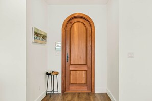 A hallway with a wooden door, a small stool, and a framed picture on the wall. - Palmilla Beach Resort-152 Sunrise Avenue (Port Aransas)