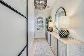 Ein Flur mit einem gemusterten Teppich, einer dekorativen Lampe und einem Spiegel auf einer Konsole.