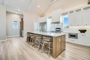 A spacious kitchen with a central island, bar stools, and modern appliances. - Palmilla Beach Resort-155 Sunset Avenue (Port Aransas)