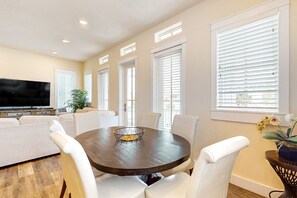 A dining area with a round table, white chairs, a television, and a plant. - Palmilla Beach Resort-157 Sunrise Avenue (Port Aransas)