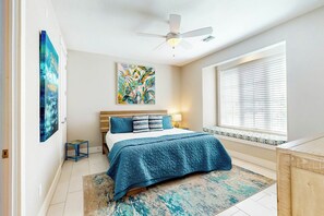 A bedroom with a bed, a ceiling fan, a window with blinds, and artwork on the walls. - Palmilla Beach Resort-160 Sunset Avenue (Port Aransas)