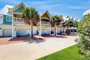 A hotel with multiple-story buildings, a covered outdoor area, and palm trees. - Palmilla Beach Resort-160 Sunset Avenue (Port Aransas)