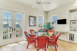 A dining area with a round table, red wicker chairs, and a ceiling fan. - Palmilla Beach Resort-161 Sunset Avenue (Port Aransas)
