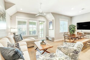 A spacious living area with a high ceiling, a ceiling fan, a dining table with chairs, a sofa set, and a television mounted on the wall. - Palmilla Beach Resort-162 Sunset Avenue (Port Aransas)
