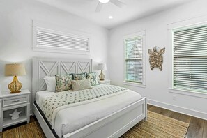 A bedroom with a bed, nightstands, lamps, and decorative wall art. - Palmilla Beach Resort-166 Spanish Dagger Lane (Port Aransas)