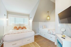 A bedroom with a bed, bedside tables, a dresser, a mirror, and a ceiling light fixture. - Palmilla Beach Resort-167 Stargrass Lane (Port Aransas)
