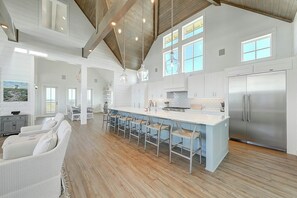 A spacious kitchen with a central island, stainless steel appliances, and a high ceiling with exposed beams. - Palmilla Beach Resort-168 Sunrise Avenue (Port Aransas)