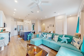 A modern living room with a teal sofa, a glass coffee table, and a ceiling fan. - Palmilla Beach Resort-169 Spanish Dagger Lane (Port Aransas)