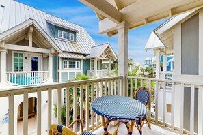 A covered outdoor area with a table and chairs, a pool, and a view of a residential building with multiple windows and balconies. - Palmilla Beach Resort-171 Stargrass Lane (Port Aransas)