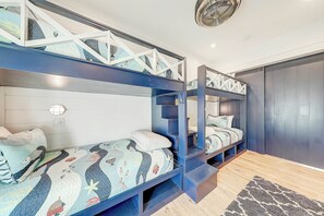 A bunk bed room with a white headboard, a built-in shelf, and a patterned bedspread. - Palmilla Beach Resort-171 Sunrise Avenue (Port Aransas)