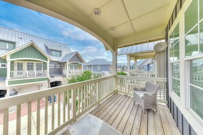 A covered balcony with a view of neighboring houses, a table, and a chair. - Palmilla Beach Resort-171 Sunset Avenue (Port Aransas)