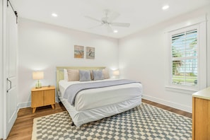 A bedroom with a bed, bedside tables, a ceiling fan, artwork on the wall, and a window with blinds. - Palmilla Beach Resort-173 Spanish Dagger Lane (Port Aransas)