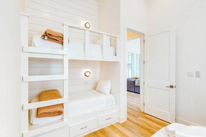 Een slaapkamer met een stapelbed, een nachtkastje en een kledingkast.