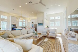 Ein geräumiges Wohnzimmer mit einer großen Couch, einem Couchtisch und einem Essbereich mit Stühlen.