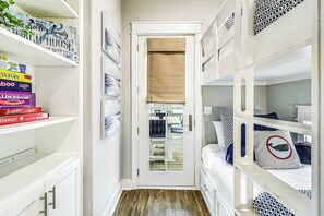 A narrow hallway with bunk beds on either side, leading to a door with a view of a balcony. - Palmilla Beach Resort-177 Sunset Avenue (Port Aransas)