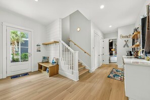 A modern interior with a wooden staircase, a kitchen area, and a dining space. - Palmilla Beach Resort-178 Sage Lane (Port Aransas)