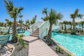 Ein Poolbereich mit Holzterrasse, Palmen und einer Treppe, die zu einem Gebäude führt.