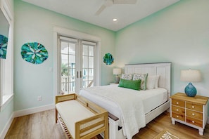 A bedroom with a bed, bedside tables, a bench, and decorative wall art. - Palmilla Beach Resort-182 Sage Lane (Port Aransas)
