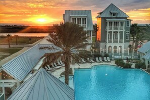 A resort with a pool, palm trees, and a sunset view. - Palmilla Beach Resort-182 Sage Lane (Port Aransas)