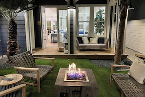 An outdoor patio with a fire pit, wicker furniture, and a view into the house. - Palmilla Beach Resort-183 Stargrass Lane (Port Aransas)
