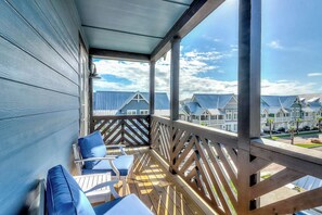 A covered outdoor seating area with wooden railings and blue cushioned chairs. - Palmilla Beach Resort-184 Spanish Dagger Lane (Port Aransas)