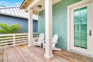 A covered porch with wooden flooring, white railings, and two Adirondack chairs. - Palmilla Beach Resort-187 Stargrass Lane (Port Aransas)