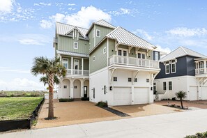 A multi-story residential building with a garage, a covered porch, and a landscaped front yard. - Palmilla Beach Resort-187 Stargrass Lane (Port Aransas)