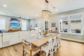A modern kitchen with a wooden dining table, white chairs, and a chandelier. - Palmilla Beach Resort-187 Stargrass Lane (Port Aransas)
