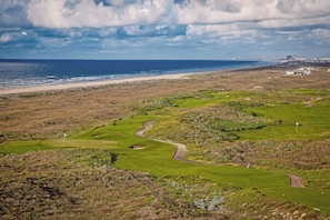 A golf course with a view of the ocean and a distant city skyline. - Palmilla Beach Resort-189 Sunset Avenue (Port Aransas)