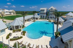 Ein Resort mit einem zentralen Schwimmbecken, mehreren Gästevillen und Blick auf den Ozean.