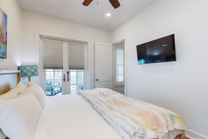 Ein Schlafzimmer mit Bett, Fernseher und Balkonblick.