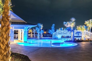 A pool area with a wooden deck, palm trees, and a covered seating area. - Palmilla Beach Resort-191 Stargrass Lane (Port Aransas)