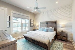 Ein Schlafzimmer mit einem Bett, einer Bank, einem Nachttisch, einer Lampe und einem Deckenventilator.