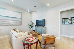 A modern living room with a sofa, armchair, and a television on a cabinet. - Palmilla Beach Resort-197 Sunset Avenue (Port Aransas)