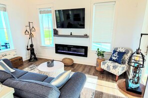Ein Wohnzimmer mit Flachbildfernseher, Kamin, Sofa und einem gemusterten Sessel.
