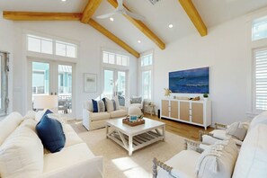 Ein geräumiges Wohnzimmer mit hohen Decken, großen Fenstern und Blick ins Freie.