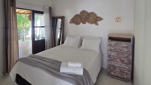 A bedroom with a bed, a ceiling fan, a wall-mounted decorative item, and a wooden dresser. - Pousada Luar de Pitinga (Arraial d'Ajuda)
