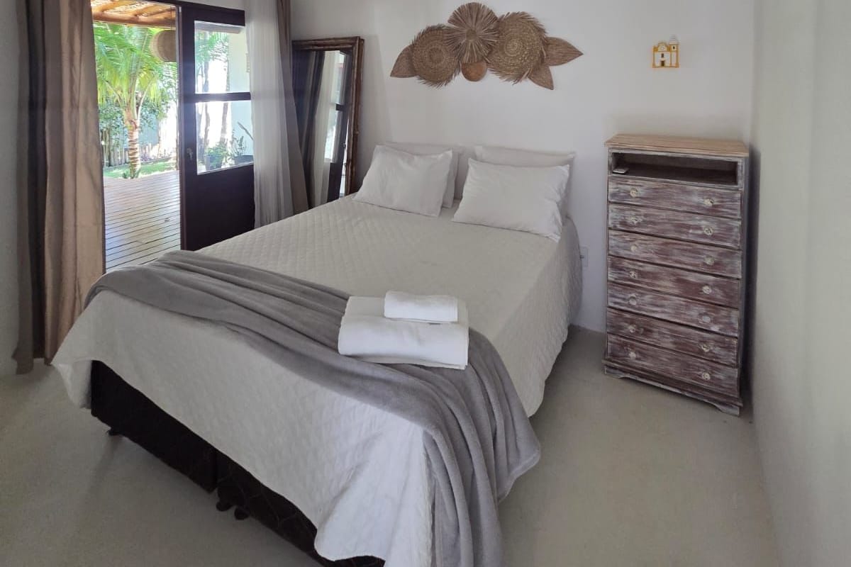 A bedroom with a bed, a ceiling fan, a wall-mounted decorative item, and a wooden dresser.