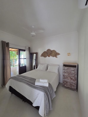 A bedroom with a bed, a ceiling fan, a wall-mounted decorative item, and a wooden dresser. - Pousada Luar de Pitinga (Arraial d'Ajuda)