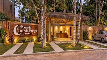 Uma área de recepção com painel de identificação, balcão de atendimento e espaço para sentar.